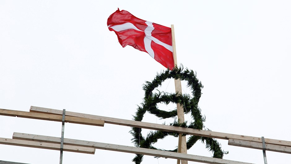 Traditionel rejsegildekrans hænger på toppen af bygning under rejsegilde